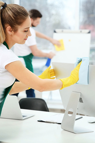 Cleans monitor. Group of workers clean modern office together at